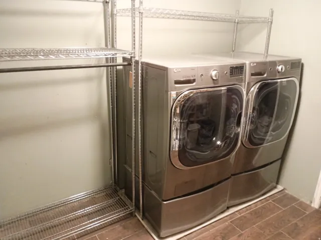Laundry area with wood-finish tile flooring, integrated shelving, and a hanging rod
