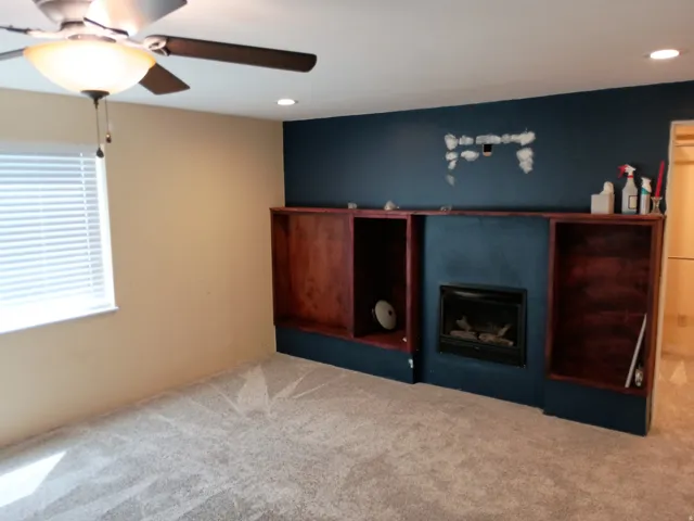 Recessed lighting, ceiling fan with integrated light, built-in shelving, gas fireplace, and carpeted flooring