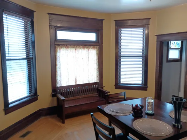 Hardwood flooring, wood trim throughout, multiple windows with blinds, recessed lighting, and a built-in window bench