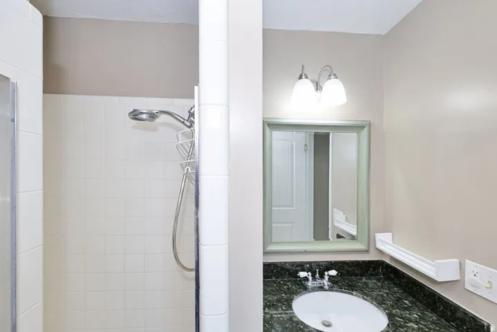 Shower with white tile surround and handheld shower head
