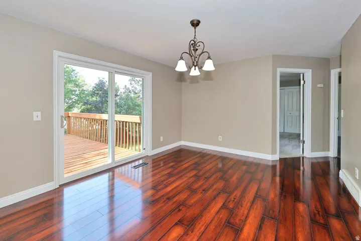 Hardwood-finish flooring, sliding glass door, overhead light fixture, wood deck, and neutral wall tones