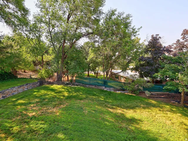 Expansive lawn area with a stone retaining wall and mature trees