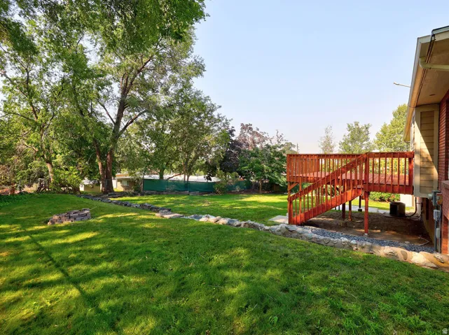 Expansive grassy lawn with mature trees and a multi-level wood deck
