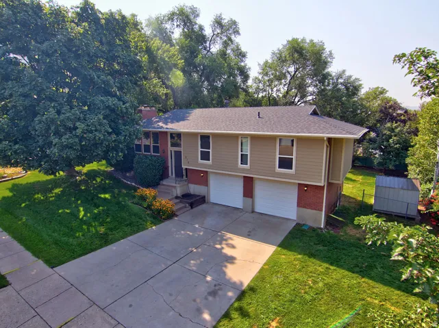 Split-level residence featuring a two-car garage, concrete driveway, and established landscaping