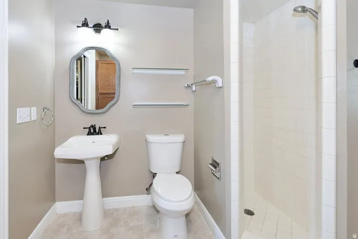 Pedestal sink with black-finish faucet, framed mirror, and two-light vanity fixture