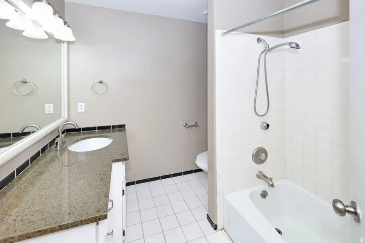Bathroom featuring a single vanity with a stone countertop, an undermount sink, and a framed mirror