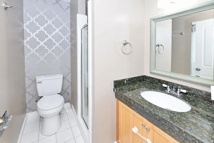 Bathroom featuring a vanity with a dark speckled countertop, an oval undermount sink, and a framed mirror