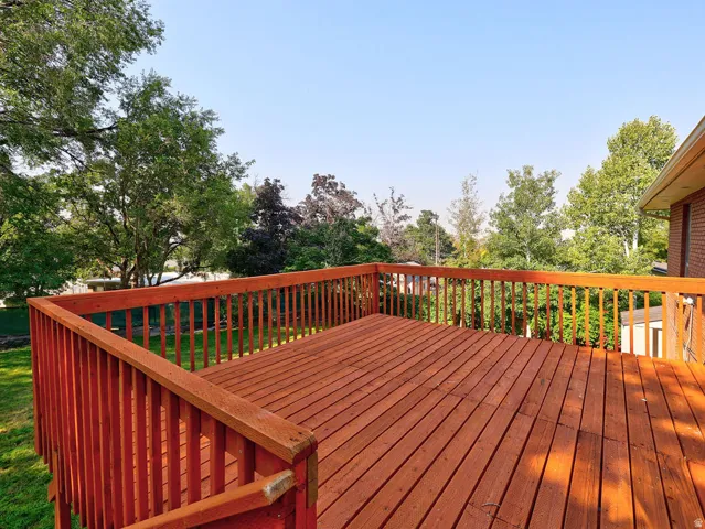 Expansive outdoor deck with wood railing and balusters, featuring rich wood-finish decking and a green lawn below