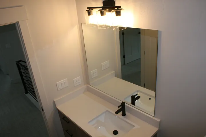 Single vanity with a light-toned countertop, integrated rectangular sink, and matte black faucet