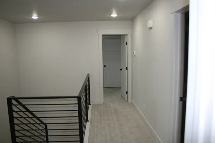 Contemporary metal stair railing, recessed ceiling lighting, light-toned wall paint, and white trim throughout