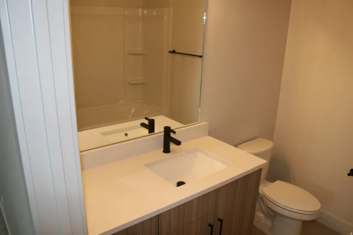 Vanity with wood-finish cabinetry, integrated sink, and dark-finish faucet