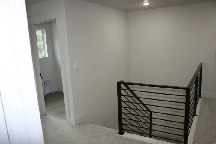 Modern horizontal bar railing, recessed lighting, neutral wall finishes, and light-tone carpeting