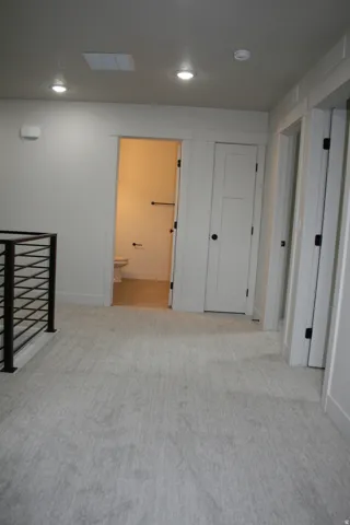Recessed ceiling lighting, light-toned wall-to-wall carpeting, and a black metal railing