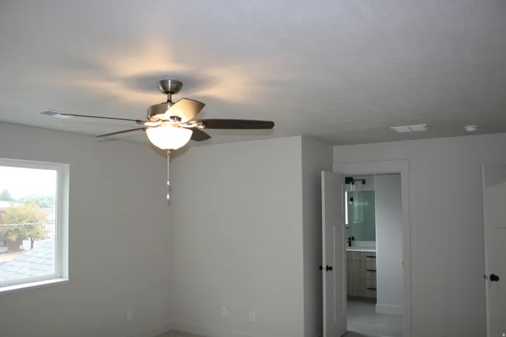 Ceiling fan with integrated lighting, wall-to-wall carpeting, and a window with white trim