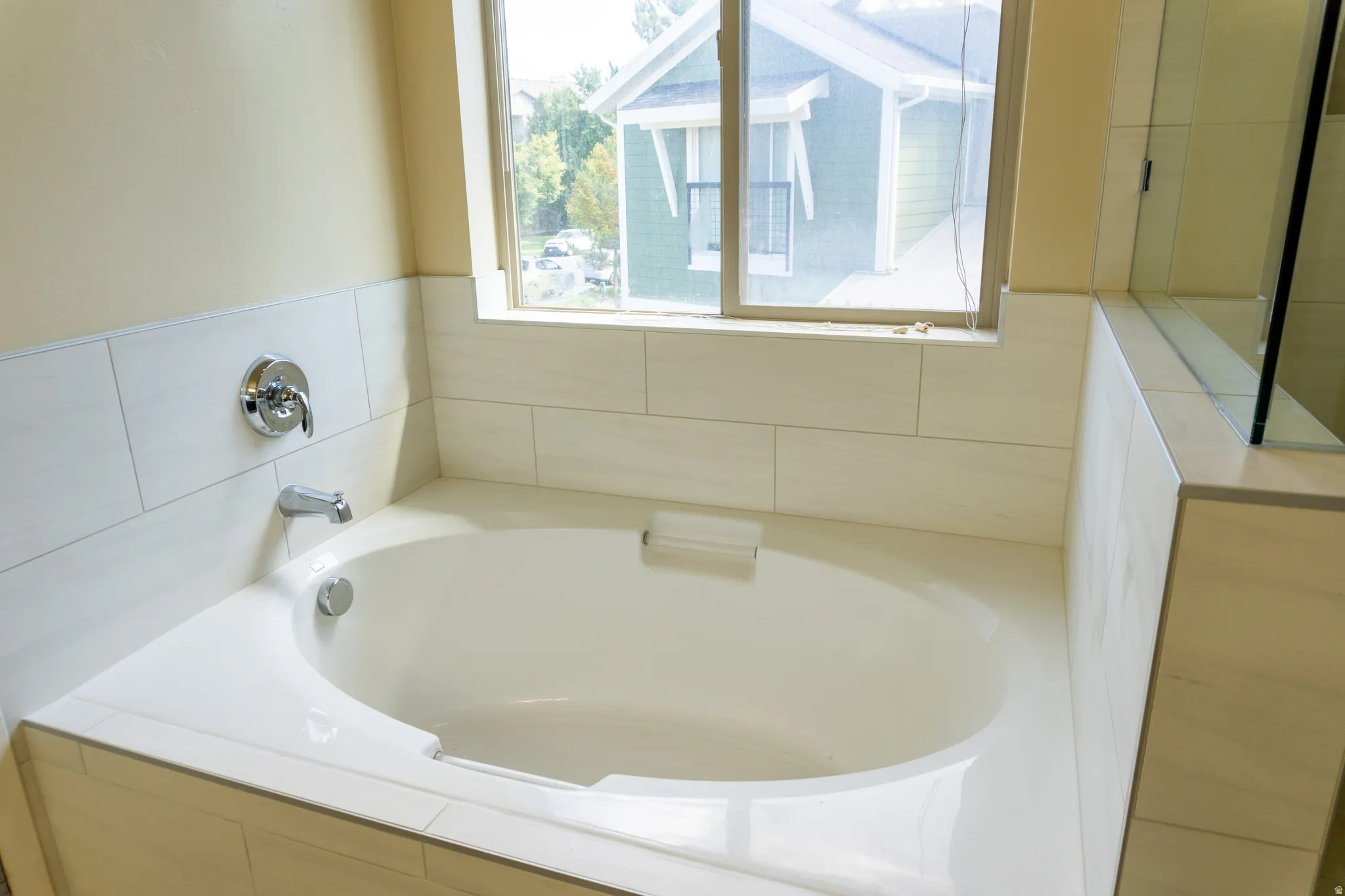 Built-in soaking tub with chrome fixtures, tiled surround, and adjacent glass-enclosed shower