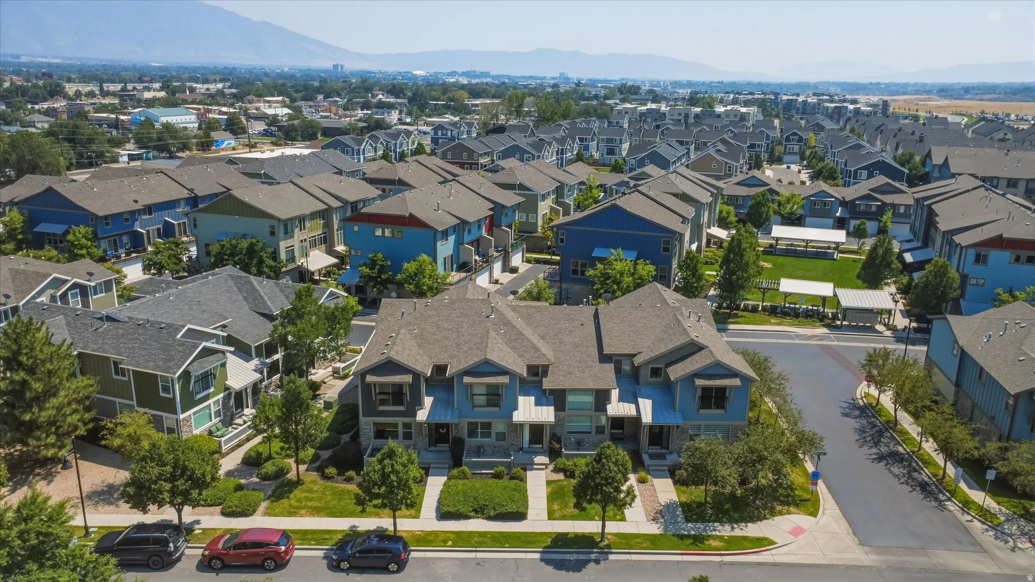 Community featuring multi-level residences, manicured green spaces, and a mountainous backdrop