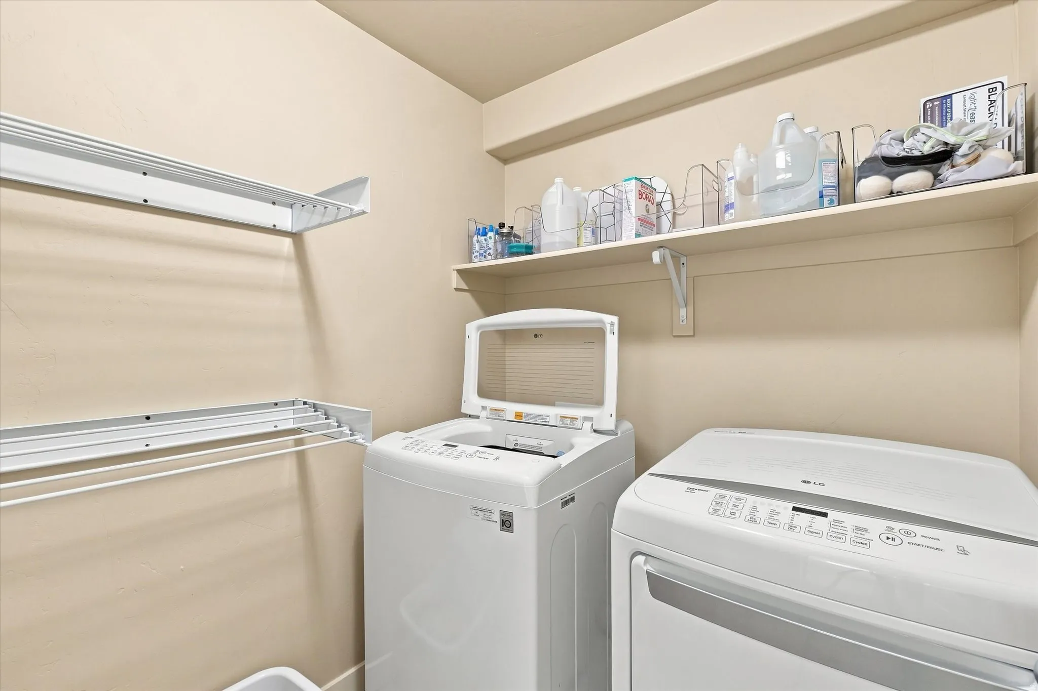 Laundry area featuring wall-mounted shelves, a top-loading washing machine, and a front-loading dryer