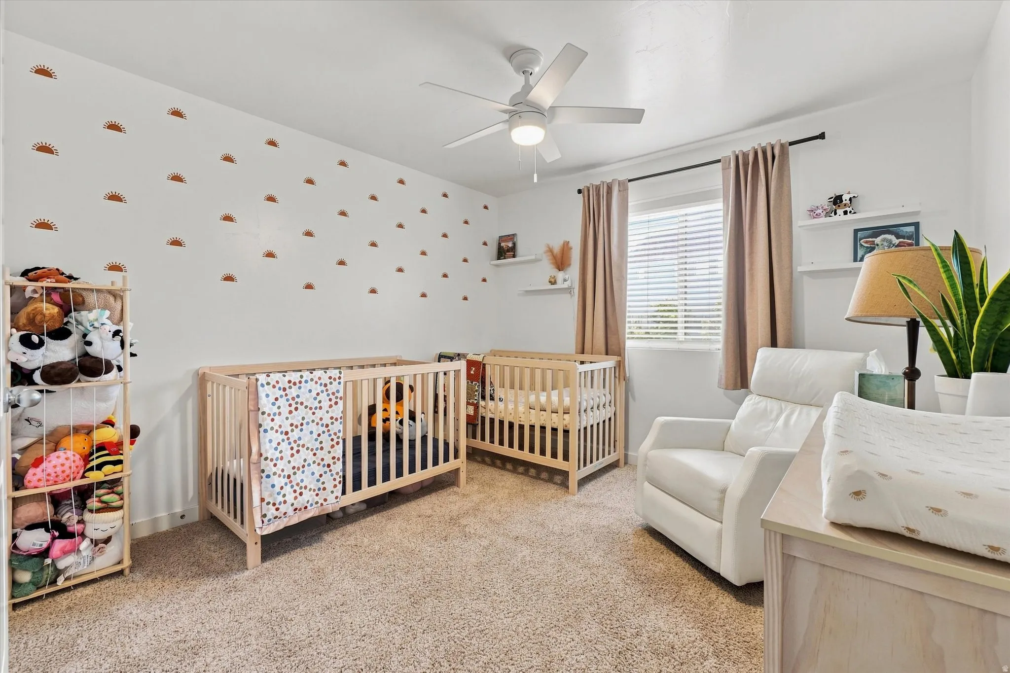 Carpeted flooring, white walls, ceiling fan, window with blinds, and floating shelves
