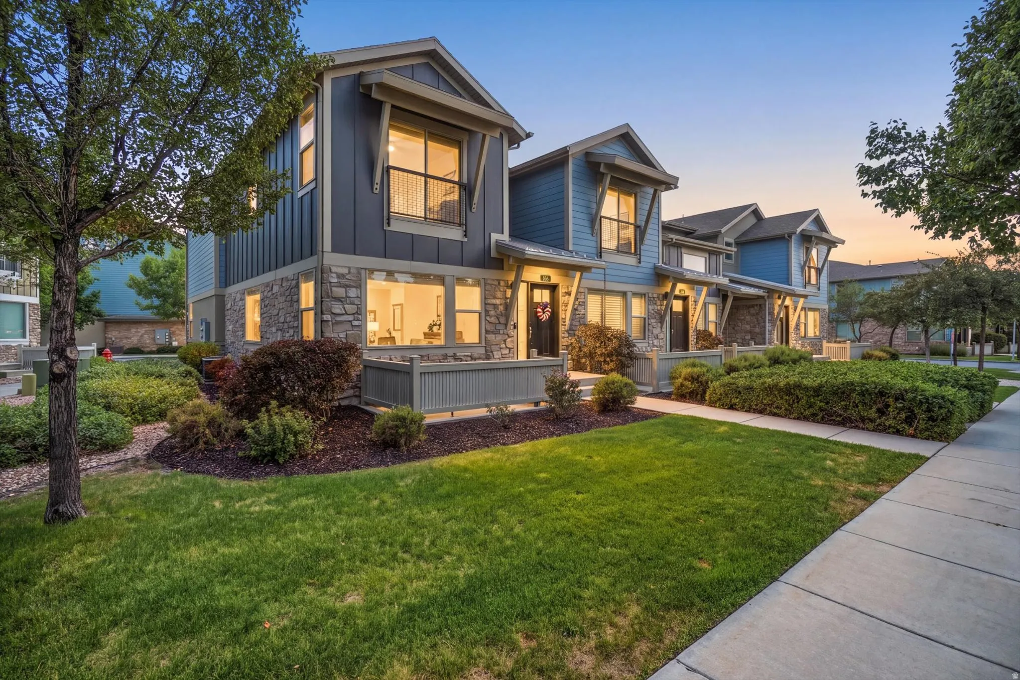 Contemporary facade with stone accents, board and batten siding, multiple windows, and landscaped grounds
