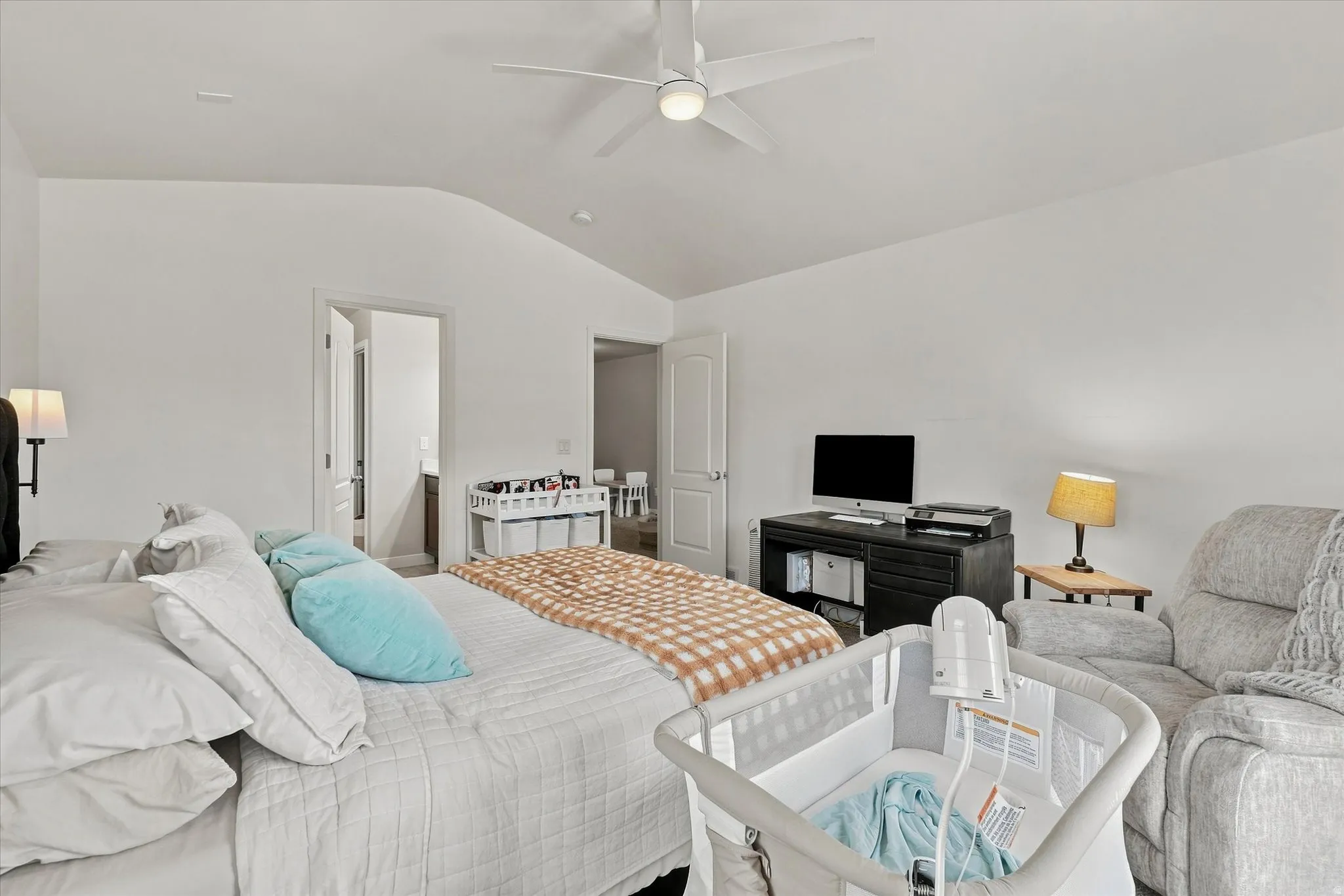 Vaulted ceiling with a ceiling fan, white walls, and a desk