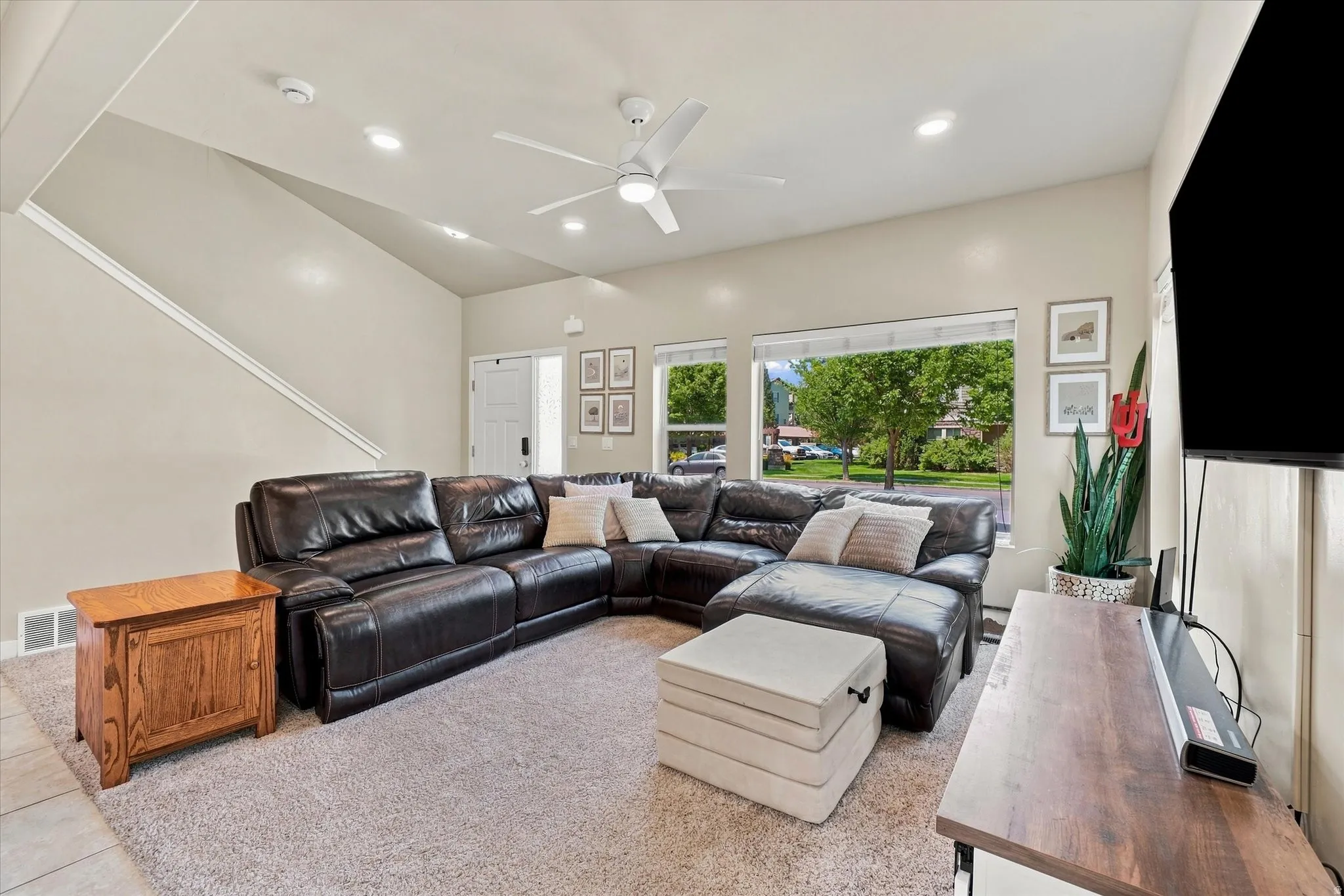 Vaulted ceiling with recessed lighting and a ceiling fan, large windows, and neutral wall tones