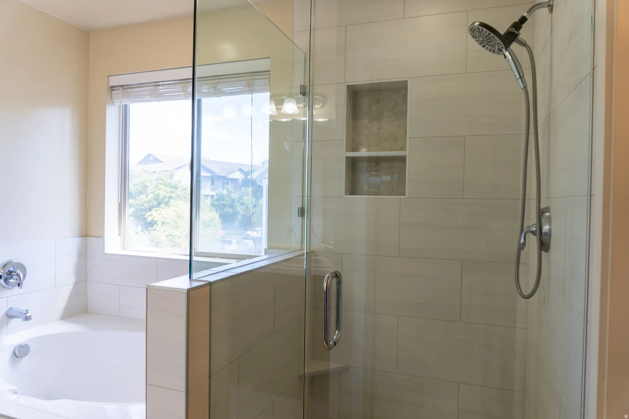 Walk-in shower with glass enclosure, integrated shelving, and a handheld shower fixture