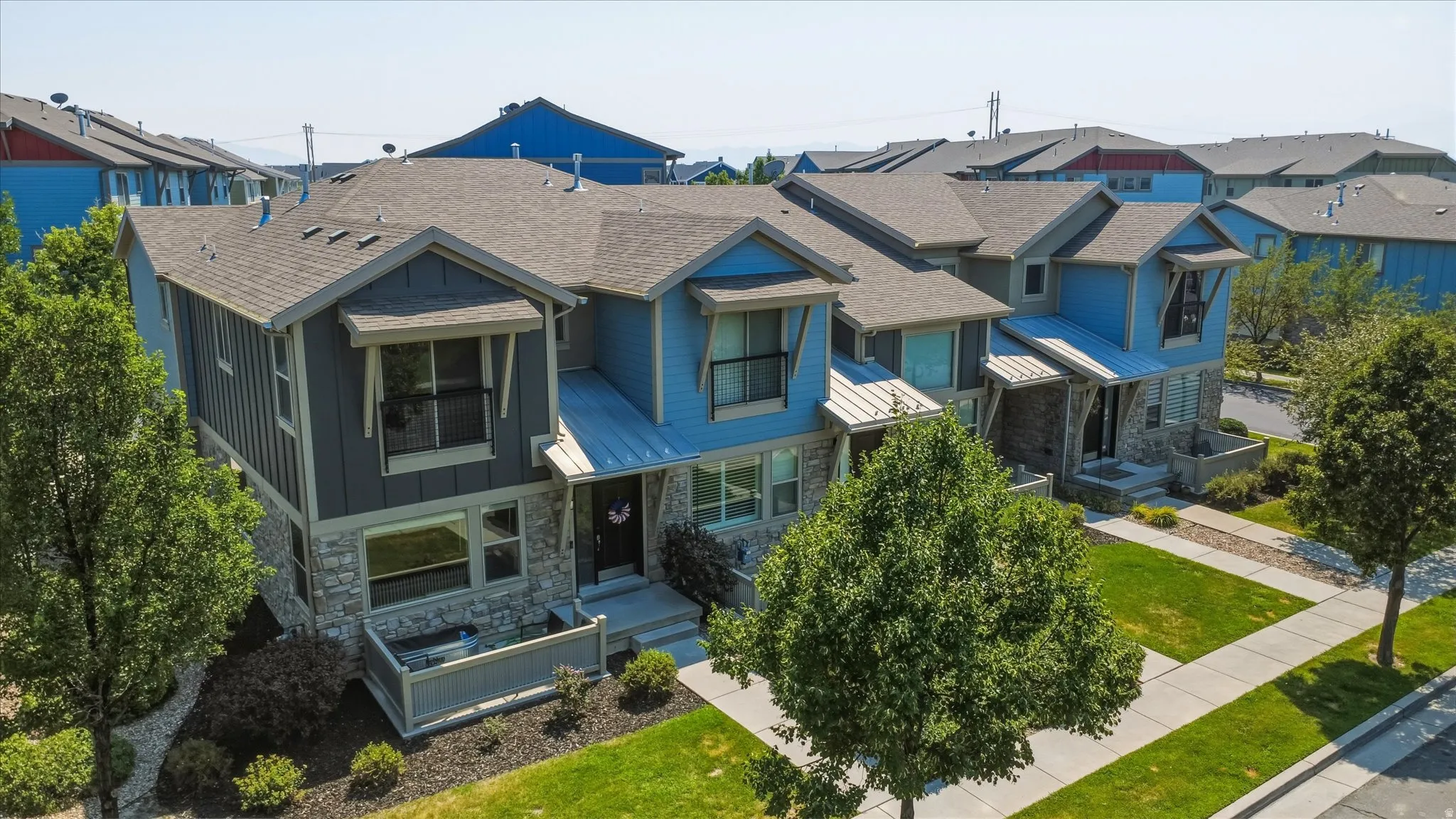 Modern exterior with mixed material siding and stone accents, featuring a covered entry and a second-story balcony