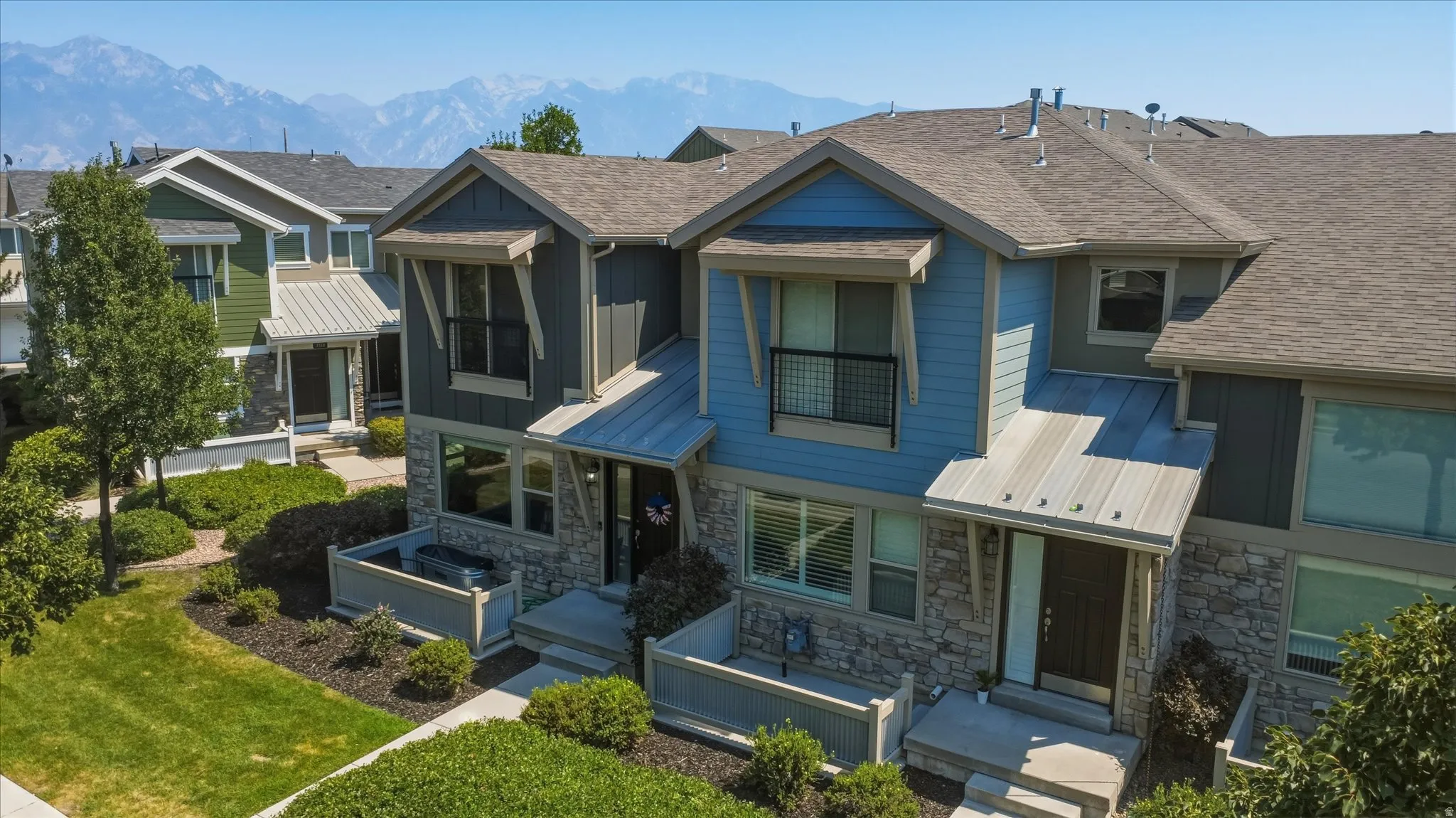 Modern townhome exterior with mixed material siding, stone accents, and a metal balcony railing