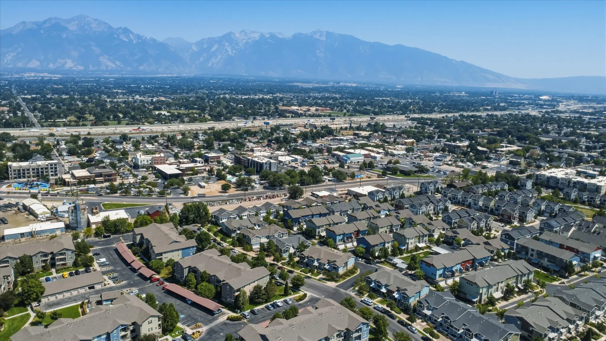 Expansive urban landscape with extensive residential development, commercial districts, and a prominent mountain range backdrop