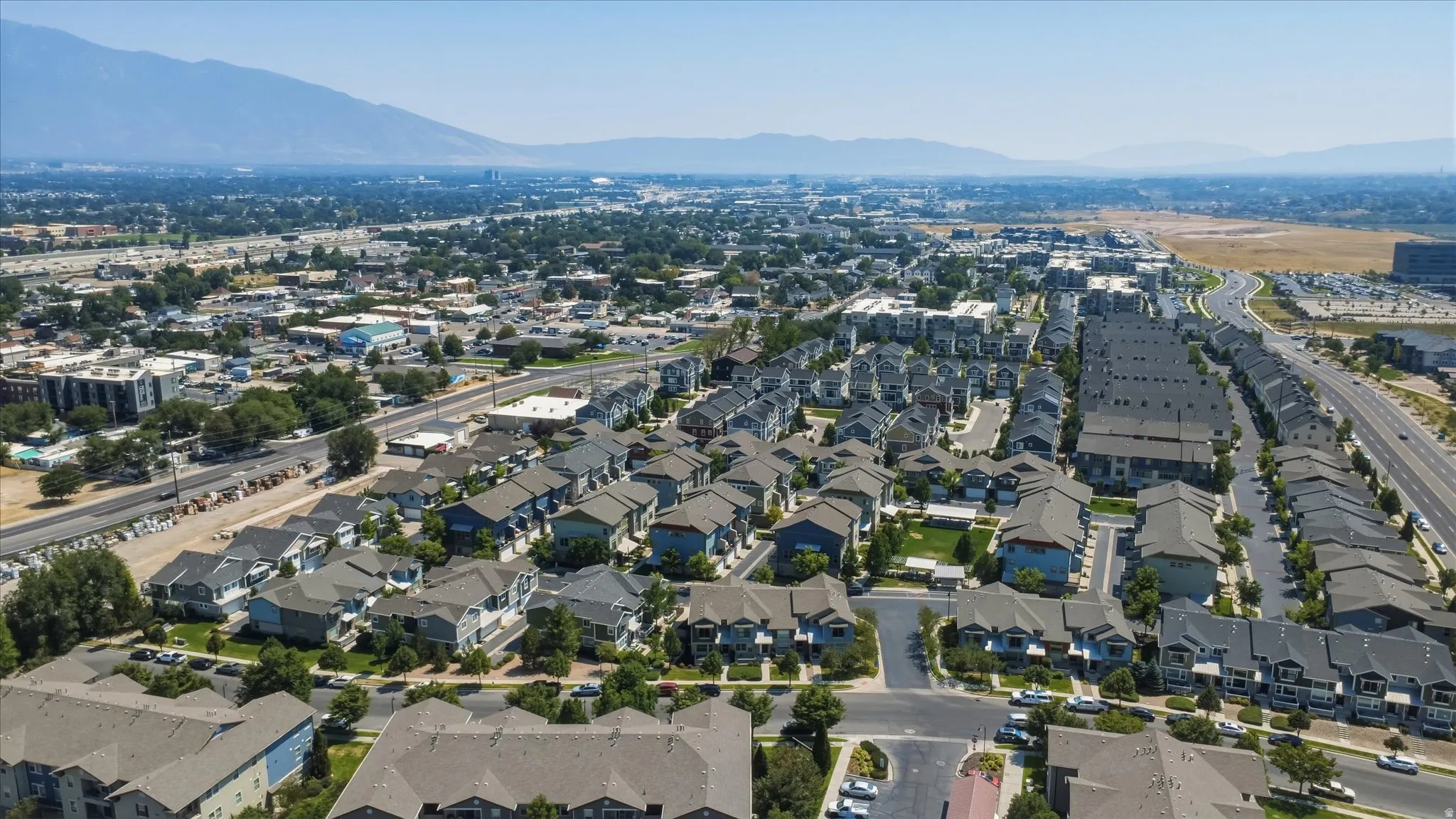 Mountain backdrop, residential development, established landscaping, paved roadways, and clear sky