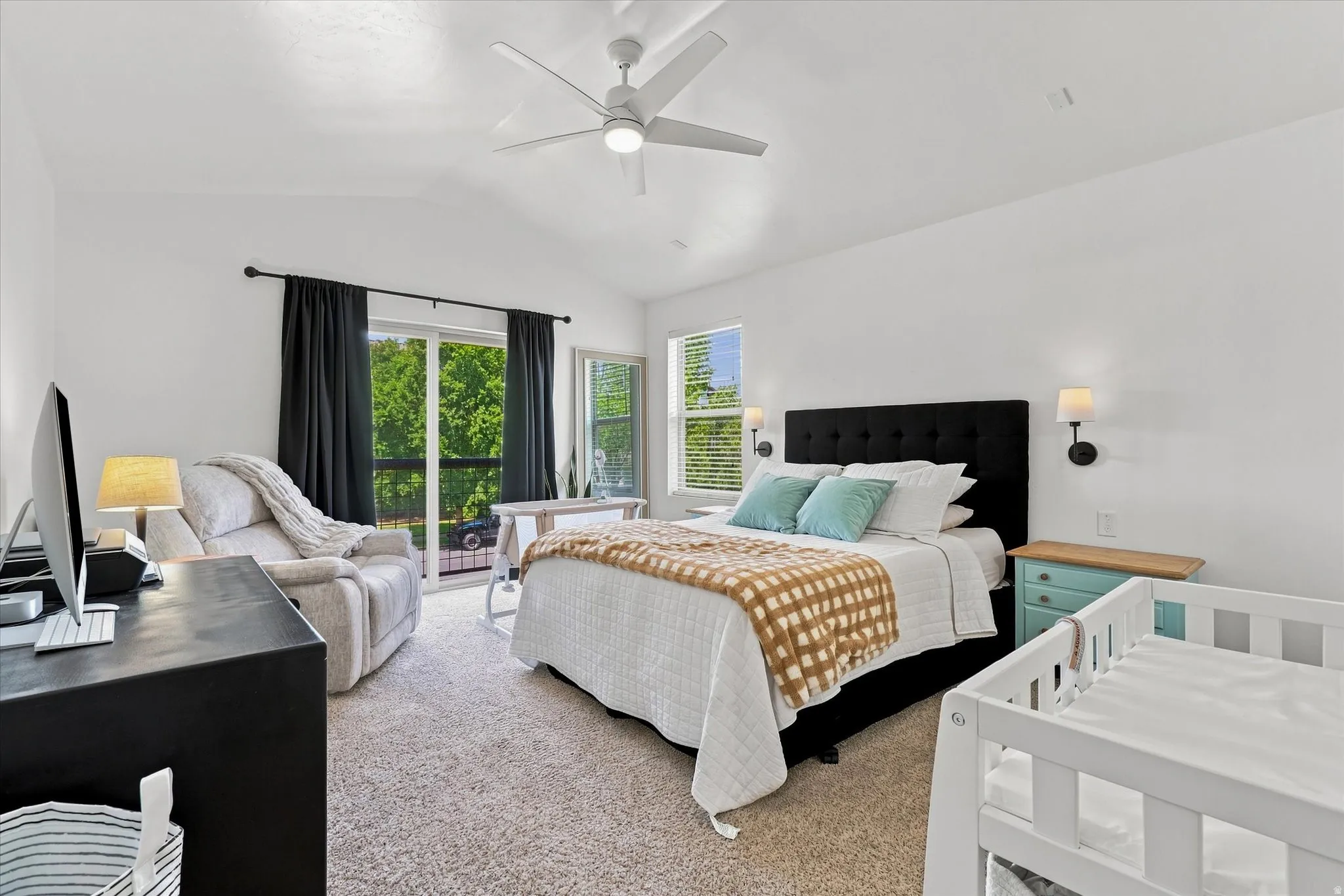 Vaulted ceiling, ceiling fan, sliding glass door, wall sconces, and carpeting