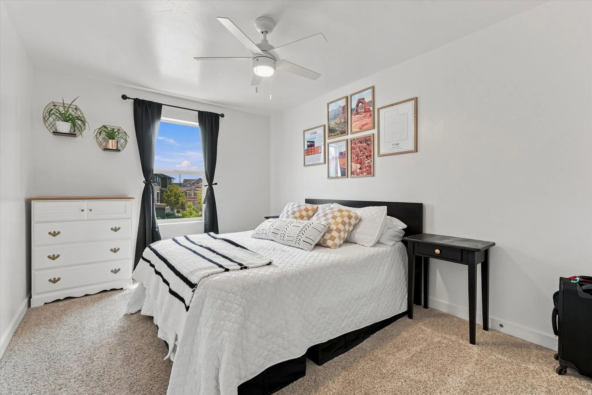 Neutral wall color, ceiling fan with light fixture, carpeted flooring, and a window with dark drapery