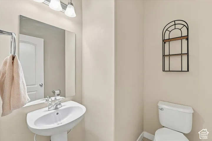 Pedestal sink with chrome faucet, wall-mounted mirror, and overhead vanity lighting