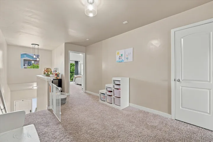 Carpeted landing with a window, contemporary pendant light fixture, and white doors
