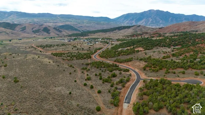 Expansive landscape featuring distant mountains, established community, and paved roads with cul-de-sac