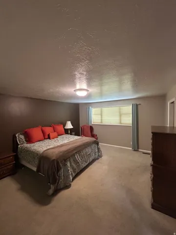 Wall-to-wall carpeting, window with blinds, overhead dome light fixture, and neutral wall tones
