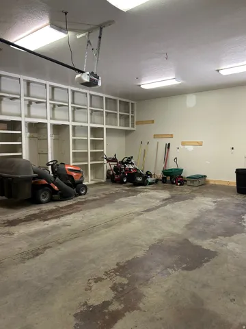 Garage featuring extensive built-in shelving, concrete flooring, and overhead fluorescent lighting