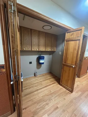 Wood-finish flooring with bi-fold doors and overhead cabinetry