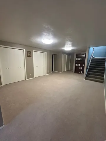 Expansive carpeted area with neutral-toned walls, multiple closet storage options, and recessed lighting
