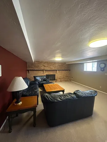 Brick fireplace feature with a raised hearth, light neutral carpeting, and recessed lighting