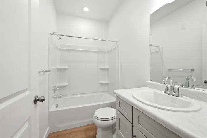 Modern bathroom featuring a single vanity with an integrated sink, a large mirror, and a shower-over-tub combination
