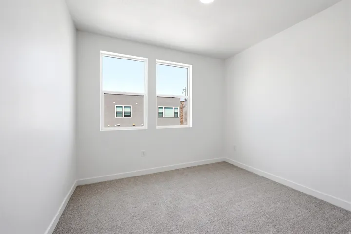 Neutral paint palette, recessed ceiling lighting, light gray carpet, two large windows, white trim