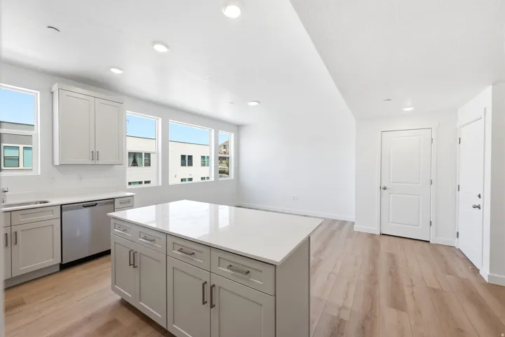 Kitchen island with a light-toned countertop, light gray cabinetry, and recessed lighting