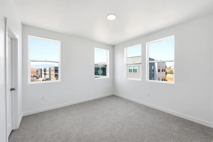 Three windows with white trim, recessed lighting, and gray carpeting
