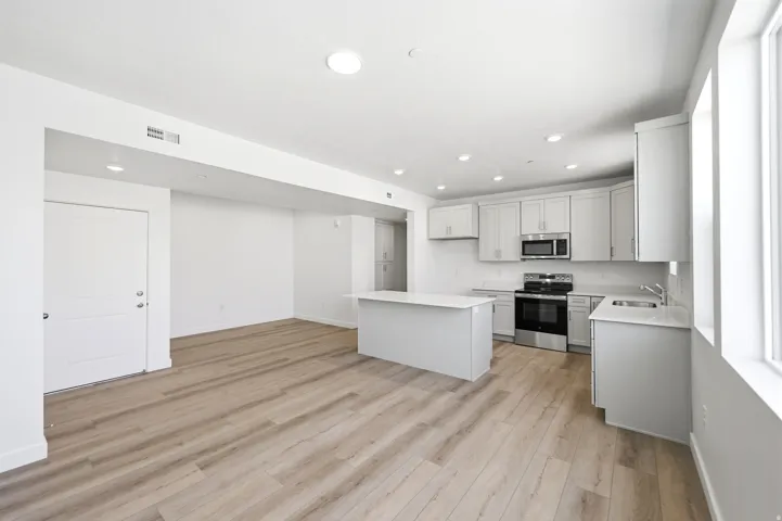 Open-concept living space with wood-finish flooring, recessed lighting, and large windows
