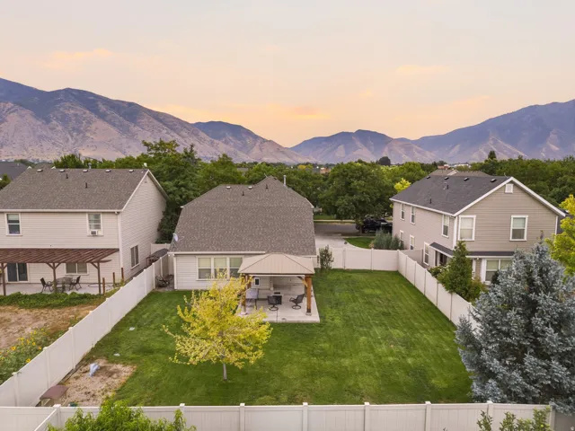 Expansive backyard featuring a lush lawn, white privacy fencing, and a built-in covered patio