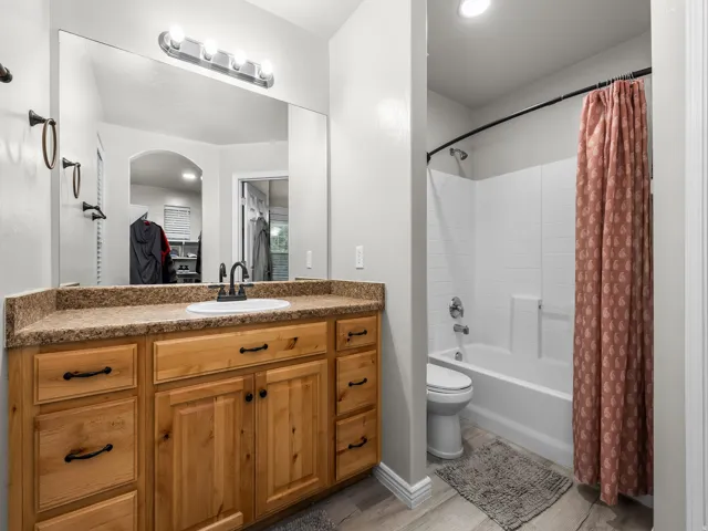 Wood-finish vanity with a single basin sink, counter space, and a large wall-mounted mirror