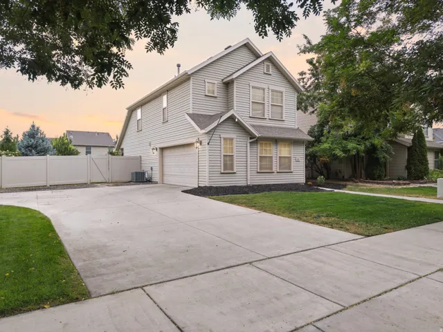 Two-story residence with light gray siding, an attached garage, a concrete driveway, and a fenced rear yard