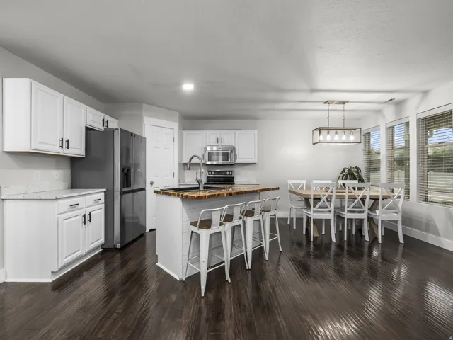 Kitchen featuring white cabinetry with dark hardware, stainless steel appliances, a center island with a wood-finish countertop, and wood-finish flooring