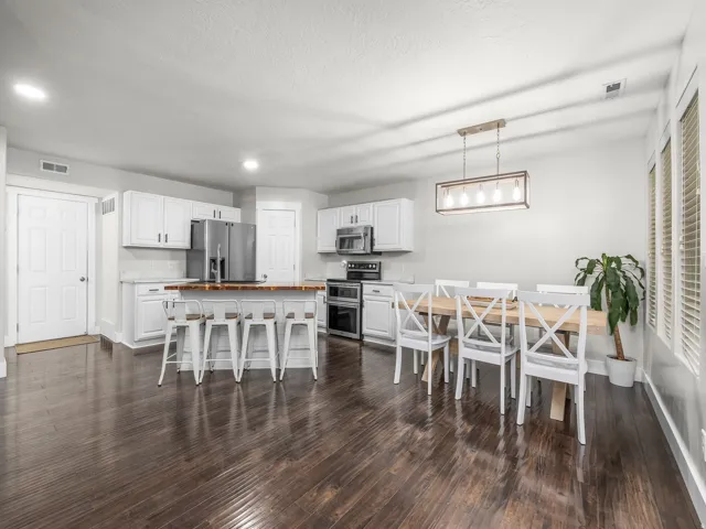 Spacious kitchen with wood-finish flooring, white cabinetry, a large kitchen island with counter seating, and stainless steel appliances
